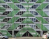 Diagonal cuts are mirrored across the facade, creating a rhythmic pattern of material and void. 