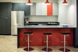 Simple Caesarstone countertops are accented by pops of color in the red bar, multi-tone cabinets, and pendant light fixtures by Troy.  Complete with Lez swivel bar stools, the break room is a great place to enjoy lunch or hold an informal meeting. 