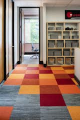 A custom pattern and color combination of FLOR carpet tiles adds variety to the flooring. Berlin shelving with Dorian bins adds functional storage.