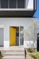 A bright yellow front door adds a bold pop of color to the minimal exterior palette. 