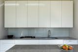 The new, high-end kitchen is a minimalist dream, complete with clean lines, flat-panel doors, and a glass backsplash.