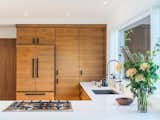 Walnut cabinets and crisp white countertops create a streamlined, modern kitchen. 
