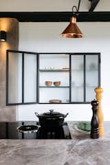 The kitchen is a contemporary installation in a 100-year-old home.   A custom, steel-and-glass cabinet is built into the wall for additional storage space, while tying in with the black steel framing above.