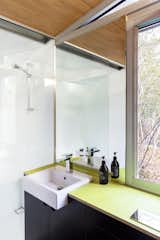 Green linoleum countertops and black cabinets reappear in the bathroom.  A south-facing window draws in plenty of natural light. Even the cabinetry and plumbing fixtures were built in the workshop.&nbsp;