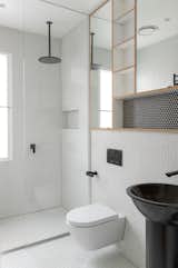 A seamless glass shower screen and matte black fixtures are contemporary additions to this sleek and simple bath.   Custom wood cubbies and penny tile on both the walls and floor add a sense of playfulness and texture to the rehabbed bathroom.&nbsp;