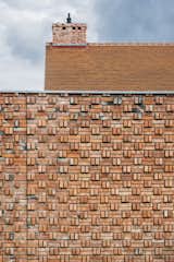 The warm, earthy tones of the brick extend to the roof line, minimizing the visual separation between wall and roof. 
