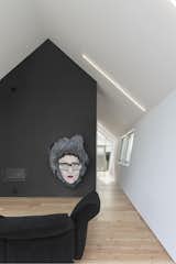 A dark wall decorated with artwork stands as a powerful contrast to the otherwise white interior. 