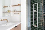 In the master bath, a custom teak vanity is accented by matching floating shelves and satin bronze fixtures. Dark green tiles from Ann Sacks add a deep, rich hue to the master retreat.