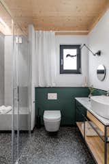 The bathroom is finished with the same green tiles as used in the chimney well.  Large-format tiles imitating terrazzo line the bathroom floor and shower walls, including the built-in bench.  