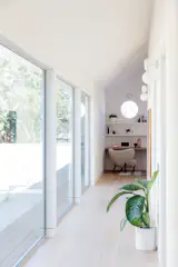 Large windows provide views to the courtyard while drawing in plentiful daylight.  Aballs Wall Sconces from Parachilna march down the hallway to a small office space with built-ins. 