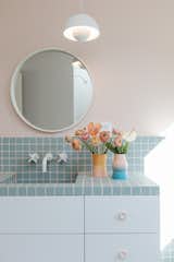 Pastel blue tile and Driklolor paint in the soft, pink Pillow hue add a touch of playfulness to the kid’s bathroom. A Flower Pot pendant light from Verner Panton hangs above the round mirror and wall-mount faucet. 