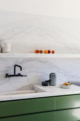 Calacatta marble dramatically extends from the counter and sink to form a backsplash and floating shelf. 