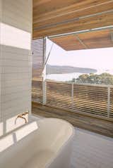 The master bath is a calming, serene retreat with broad views of Wallis Lake. Again, wood screens provide protection from the elements while allowing light to filter in.&nbsp;