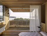 Layered facade materials allow for cross ventilation, protect from the sun, and add privacy. In the master bedroom loft, wood screens create an opportunity to be outdoors without becoming too beaten by the sun, and white curtains create another gauzy partition.