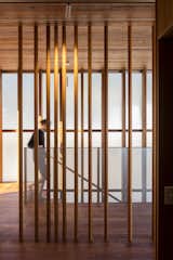 Vertical wood post act as a screen between circulation and sleeping spaces. An exterior, double-height wall of translucent Rodeca cladding extends along the staircase, leading you to the master bedroom loft.