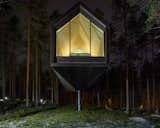 The gable-framed cabin hovers gently above the ground, blending in with the tall&nbsp; trees.&nbsp;