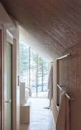 Upon entry, full-height glazing with a stunning view of the forested surroundings pulls you in, blurring the boundary between inside and outside. The cabin’s utilitarian areas are located in the center of the plan, so the remainder of the space remains open.