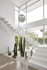 The Poul Henningsen pendant lights the stairwell. A cactus garden runs the length of the front yard and extends into the house.
