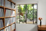 Bedroom with built-in wood shelves for records.  Steel window with view to rear yard landscape and firepit
