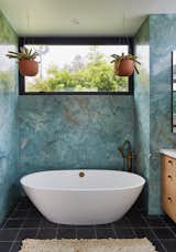 Privacy and natural light:  Hanging plants in the bathroom with clerestory windows framing the neighborhood tree canopies beyond.  Blue marble, black Cle cement floor tiles, white oak cabinetry and white mosaic tile backsplash are complimented with French Bronze plumbing fixtures from Rohl.