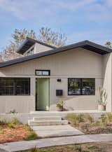 Concrete porch and hardscape as well as aluminum siding clad exterior walls were selected for their maintenance-free appeal. The eaves were painted black to match the window frames. Punctuated by a painted front door in pale green to match the olive tree leaves in the side yard.