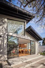 Like the front, the rear yard concrete porch steps as well as aluminum siding clad exterior walls were selected for their maintenance-free appeal. The eaves were painted black to match the window frames. A strong connection to the existing pear tree from the inside family living space was prioritized with a large clerestory window and sliding doors framing the yard.