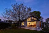The punched openings of this family home act as a lantern at dusk to the backyard with legacy pear tree. In Venice, Los Angeles this single story house features dramatic ceilings with generous clerestory windows. The family room and primary bedroom open to the rear yard. Gorgeous black walnut cabinetry with artisan tile walls as well as fumed oak flooring bring a classic California modern feel to this abode.