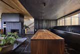 An assemblage of textures and raw materials, the great room spaces are distinguished by two unique ceiling heights: A dark-hued, minimalist layout for the kitchen opens to living room with panoramic views of the canyon to the left and the street on the right. We dropped the kitchen ceiling to be lower than the living room by 24 inches. There is a roof garden of meadow grasses and agave above the kitchen which thermally insulates cooling the kitchen space. Wood siding of the exterior wraps into the house at the south end of the kitchen concealing a pantry and panel-ready column, FIsher&Paykel refrigerator and freezer as well as a coffee bar. Soapstone counter top, backsplash and shelf/window sill, Brizo faucet with Farrow & Ball "Pitch Black" painted cabinets complete the edges. The smooth stucco of the exterior walls and roof overhang wraps inside to the ceiling passing the wide screen windows facing the street. An American black walnut island with seating also separates the kitchen and living room - all sitting on the black, irregular-shaped flagstone floors which circuit throughout the entire first floor. Walnut stair treads and handrail beyond with a solid white oak ceiling for a warm balance to the dark floors. Delta Light fixtures were used throughout for their discreet beauty yet highly functional settings.