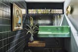 Antique cast iron sink is retrofitted, re-glazed then wall hung. Combined with a simple black Daltile in  an open wet room shower with brass sconces from Anthropologie