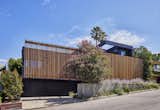 Street view with flush garage door clad in charcoal-stained reclaimed wood. A cantilevered wood screen creates a private entrance by passing underneath the offset vertical aligned western red cedar timbers of the brise-soleil. The offset wood screen creates a path between the exterior walls of the house and the exterior planters (see next photo) which leads to a quiet pond at the top of the low-rise concrete steps and eventually the entry door to the residence: A vertical courtyard / garden buffer. The wood screen creates privacy from the interior to the street while also softening the strong, afternoon direct natural light to the entry, kitchen, living room, bathroom and study. 