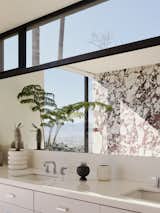 Mirror + window magic: Floating vanity with wall to wall mirror under clerestory window frames the San Fernando Valley floor beyond.