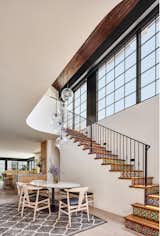 Stair to reading room mezzanine above with dining room open to kitchen, living room and yard beyond