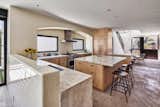 Tiled kitchen with birch cabinetry opens to outdoor dining beyond windows. Entry with stair to second floor and dining room.