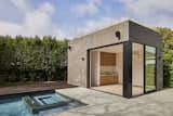 Detached pool house ADU with planted meadow grass roof opens to a swimming pool and spa surrounded by a concrete patio and raised wood deck.