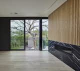 This bedroom with gas fireplace is located to frame the 50-foot tall existing Elm tree outside. The sliding door is outfitted with a Juliette balcony so one can nearly climb the tree. The fireplace is clad with Nero Marquina marble and fluted wood wall panels. In the distance one can see the residence's pool house ADU