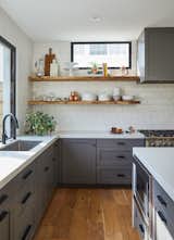 Floating shelves made from slabs of white oak run between the tile backsplash. The kitchen is fitted with a full Fisher & Paykel suite of appliances as well as French gray shaker panel cabinetry and restoration hardware cabinetry pulls and knobs. Clerestory windows allow for south-facing natural light exposure throughout the day