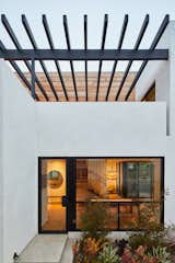 Side entrance off of driveway allows for ease of grocery drop off. The vertical lines of the stair guardrail within the house beyond connect to the horizontal lines of the pergola over the second floor family room deck above. 