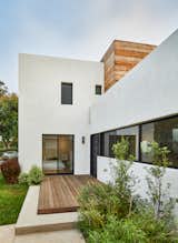 Front entry with deck - smooth white plaster and wood siding punctuated by dark bronze windows and doors. 
