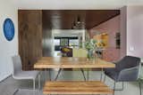 The dining room sits at the threshold between the garden and the interior. The exterior concrete floor blurs the threshold between outside and inside continuing into the dining room. The wood flooring wraps up the walls and ceiling in the kitchen creating a "wood womb": A complimentary contrast to the the pink and sea-foam painted custom cabinets, brass hardware, brass backsplash and brass island. Windows were intentionally placed on both ends of the kitchen to create a cozy space.