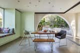 The dining room is a theater stage as the smooth stucco'd, parabolic curved opening frames the view of the food forest (and bistro patio) beyond via a corner unit of aluminum framed sliding glass doors that have been pocketed into the walls. The exterior concrete floor blurs the threshold between outside and inside continuing into the dining room. The deep window seat offers a place to read with the constellation pattern of recessed ceiling lights overhead.