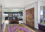 The entry features a 5-foot wide and 5-inch thick antique door made of redwood! A reclaimed door found in a local salvage yard that with a little sweat equity revealed the wood below 7-layers of paint. The entry opens to the living room with views of the hillside beyond. Also, a built-in desk nook is fitted under the stairs. The cove ceiling is painted a light sea-foam color while the media cabinets and wall are painted black to obscure the television.