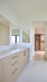 Vaulted ceiling primary bath with walk-in closet beyond