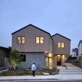 Luxury modern townhouses by Hsu McCullough at dusk. Two separate residence - detached with shared driveway. Modern Mill wood siding with a pale blush finish wraps the second floor exterior with Anderson windows. Smooth stucco at ground floor with a metal dutch door by Pinky's marks the entrance to both homes.