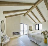 Primary bedroom with exposed beams of the vaulted ceiling and a Portola lime wash fireplace surround