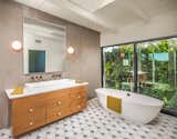 The master bath offers additional custom features with American walnut custom vanities, Venetian plaster in a concrete finish throughout the shower, a Wetstyle trough sink, and a Victoria & Albert tub with antique brass fixtures from Australia-based Brodware.