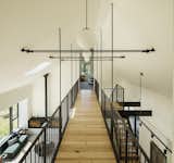 An upper level includes a den and a bunk room connected by a steel and wood staircase and bridge. 