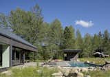 The house opens up to a view overlooking a meadow, complemented by an in-ground pool and a cedar hot tub that enhance the outdoor space.
