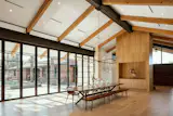 The custom walnut dining table centers on the main central axis of the courtyard as well as the entry axis of the modern addition. Exposed beams run from inside to out. Lights and diffusers in the ceiling are aligned based on the structural spacing of the beams. The dining room window wall is a folding door system which opens the dining room completely to the exterior and has motorized shades to control sun when needed.