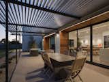 Main entertaining patio at dusk.  The trellis beams above are space more tightly as they get closer to the house, in order to help with sun control.  Linear light fixtures are integrated into the Ipe ceilings.  Sand finish concrete patios compliment the ground concrete floors on the inside of the home.