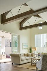 Custom beams, large windows, and wood floors offer warmth to the living room which connects to outdoor living spaces. 